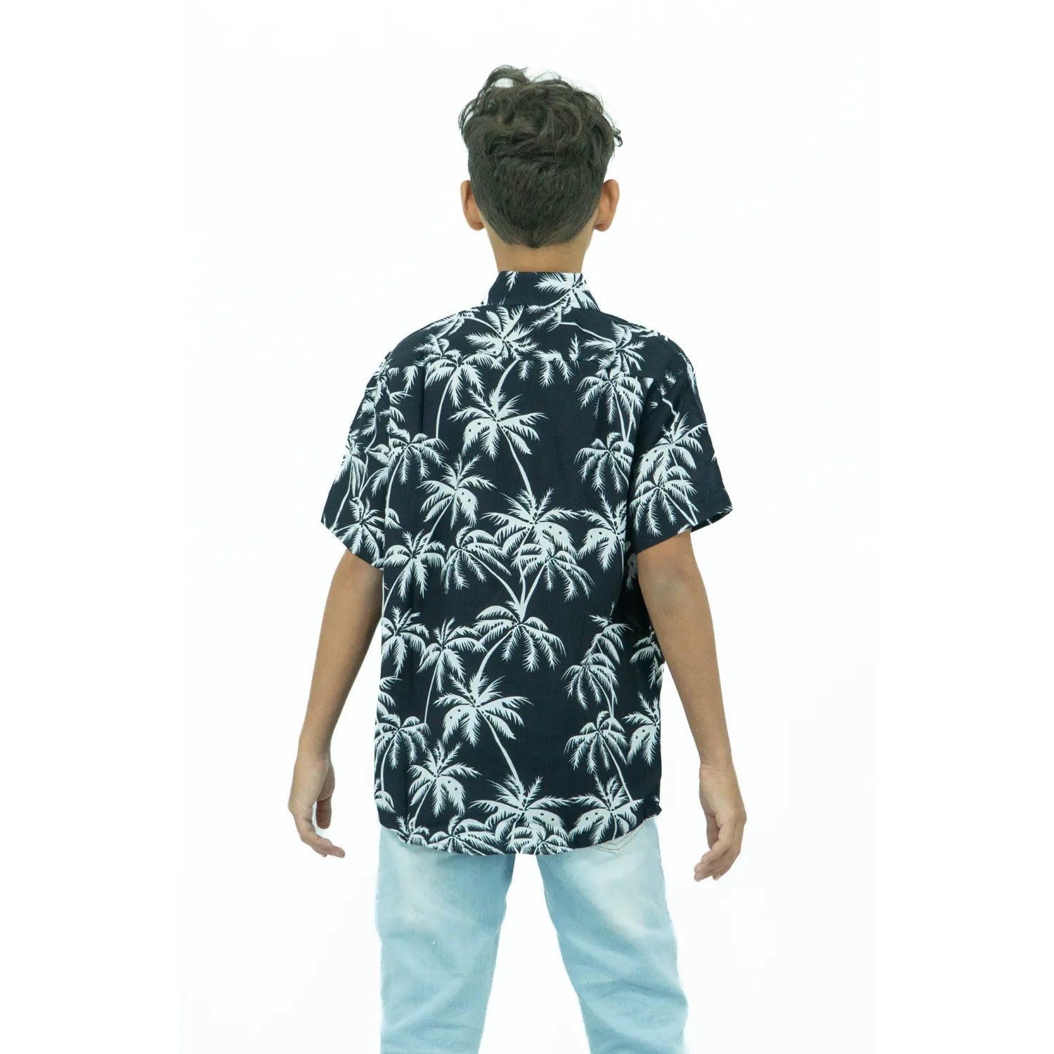 Modelo infantil de costas usando camisa social de viscose, de manga curta e com estampa de coqueiro da Absinto Men na cor preta.