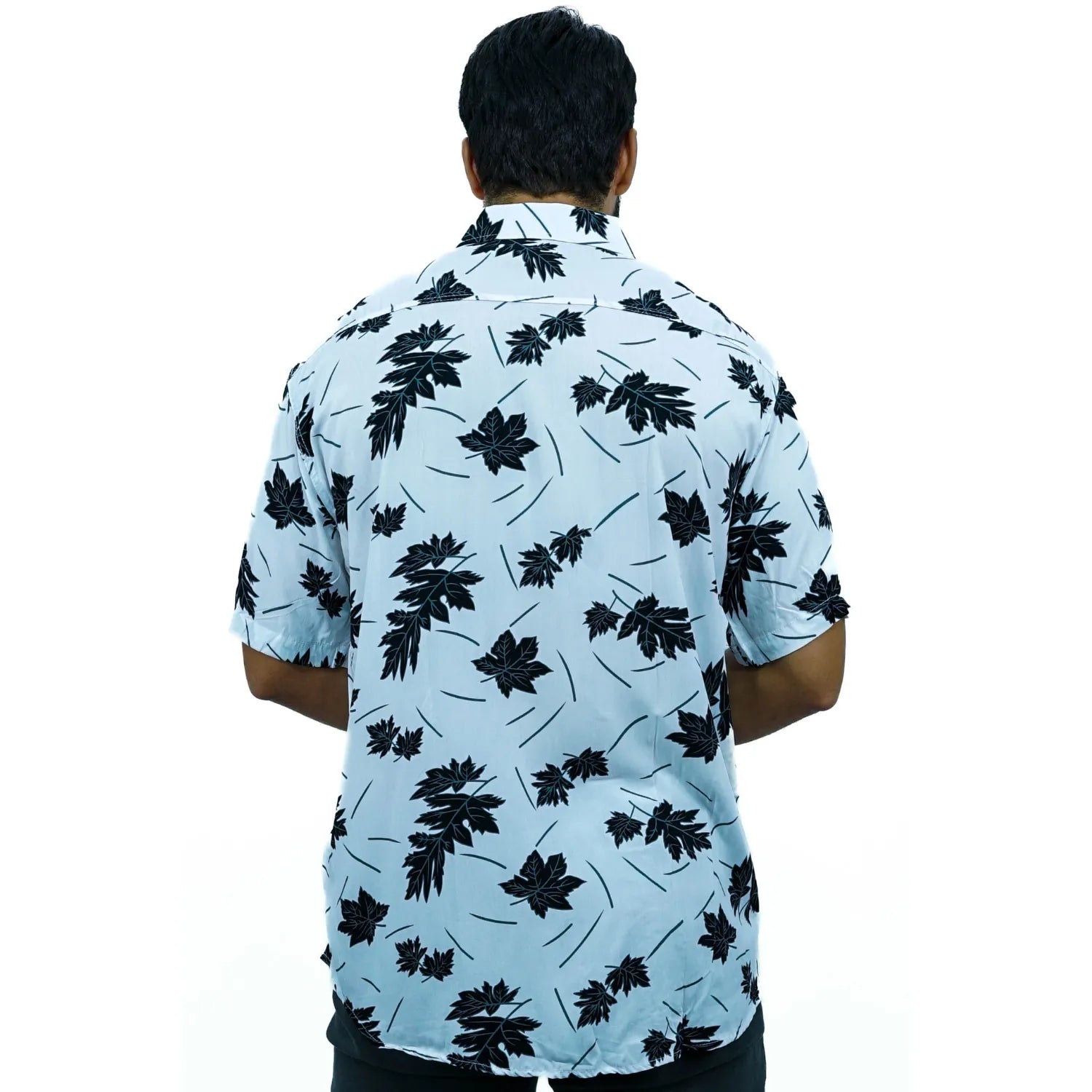 Modelo usando camisa social de viscose, de manga curta e com estampa de folhagem, na cor preta.