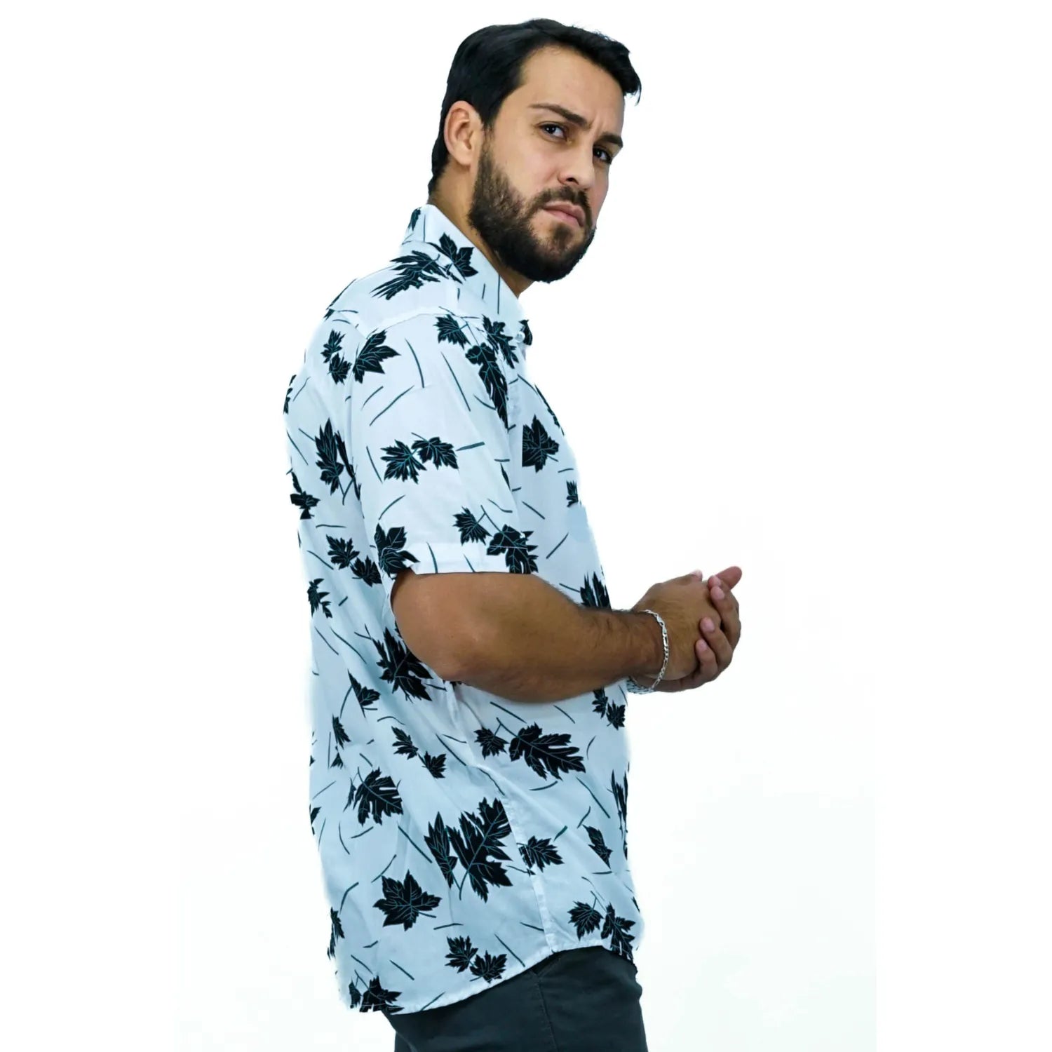 Modelo usando camisa social de viscose, de manga curta e com estampa de folhagem, na cor preta.