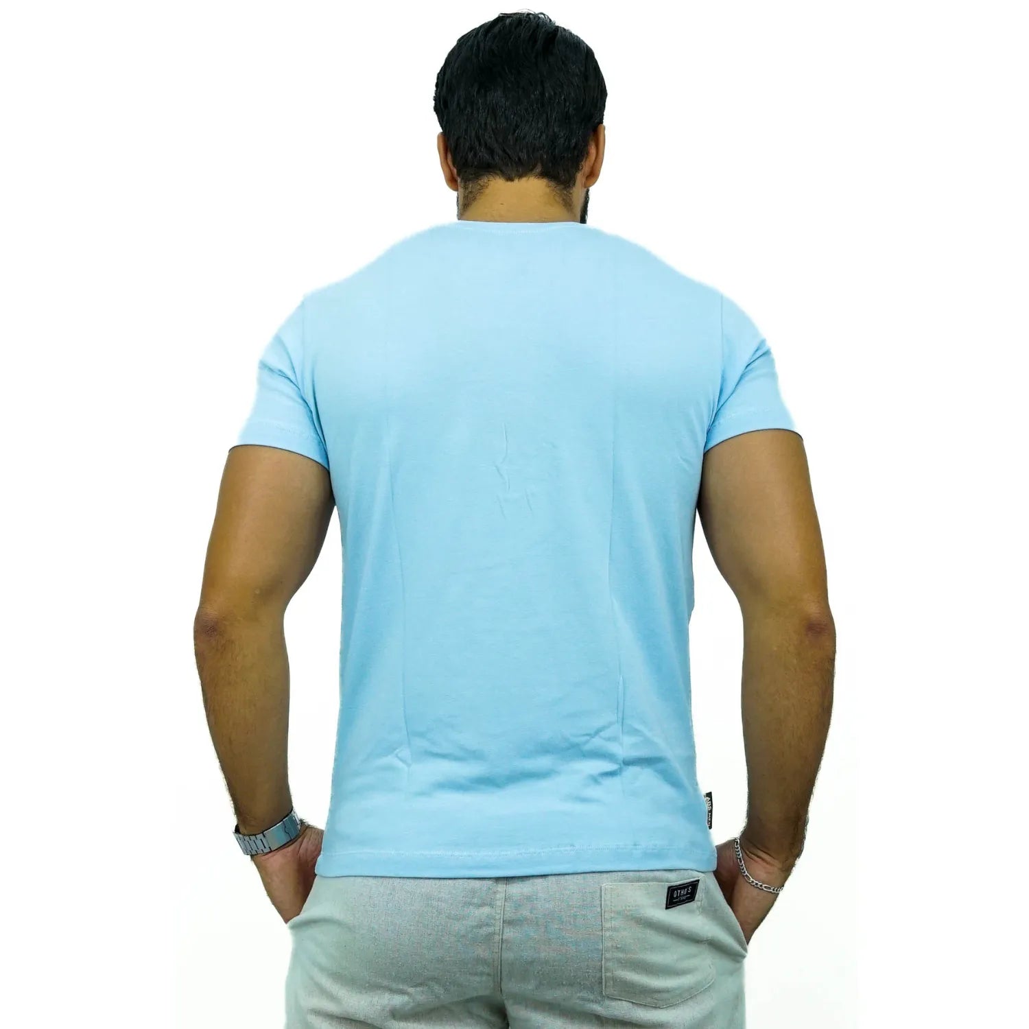 Modelo usando camiseta lisa de algodão e elastano com logo bordada da Absinto Men na cor azul bebê.